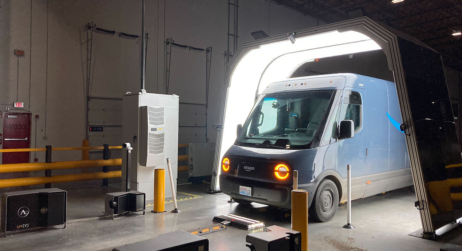 Real photo — Amazon Rivian van driving through the AVI inspection tunnel at a delivery station